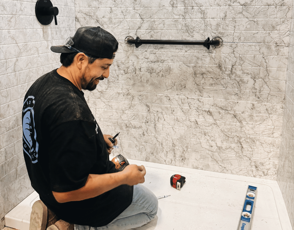 Contractor installing shower remodeling features with tile walls and updated bathroom fixtures